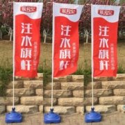 青岛开业户外场景：三套注水旗并排，可见蓝色注水底座、高杆与竖向旗面