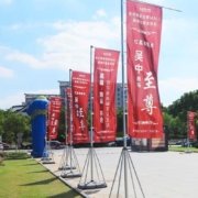 青岛园区路边户外场景：多套5米级注水旗并排，可见注水底座、高杆与竖向旗面