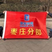青岛厂旗实拍：红色矩形公司旗帜横幅展开，左侧可见白色旗筒，属司旗号型旗面而非注水道旗